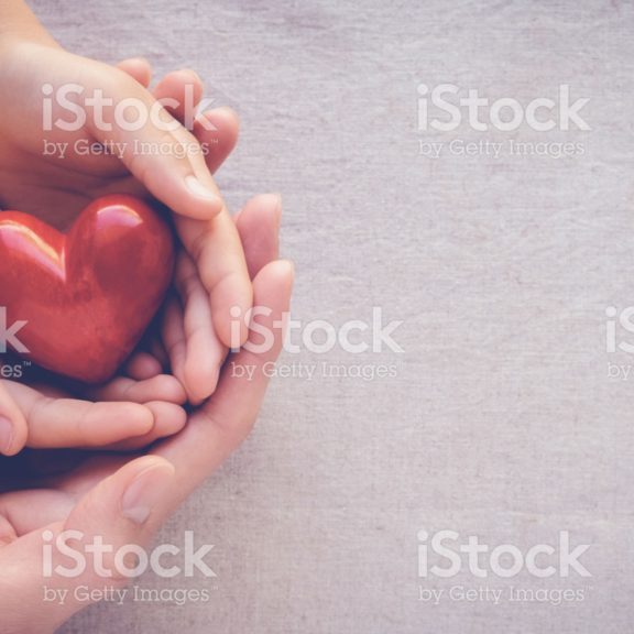 adult and child hands holding red heart, health care love and family concept